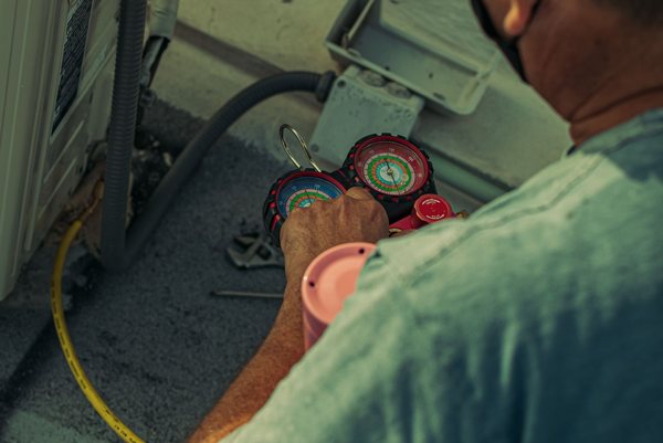 HVAC technician checking refrigerant gauges on an air-conditioning unit